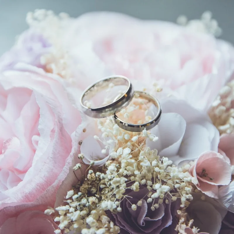 Mãos entrelaçadas com alianças de casamento